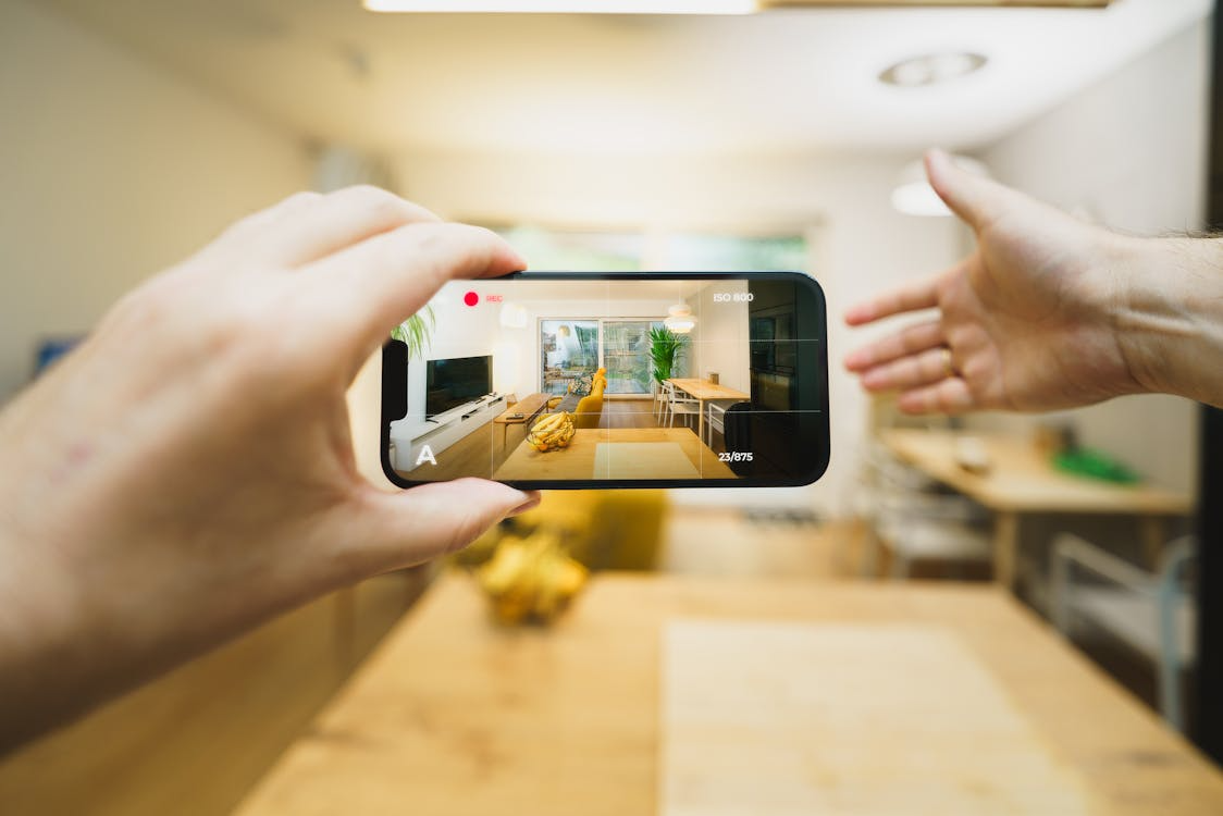 Person recording a bright staged home interior on a smartphone to showcase the space for real estate marketing.