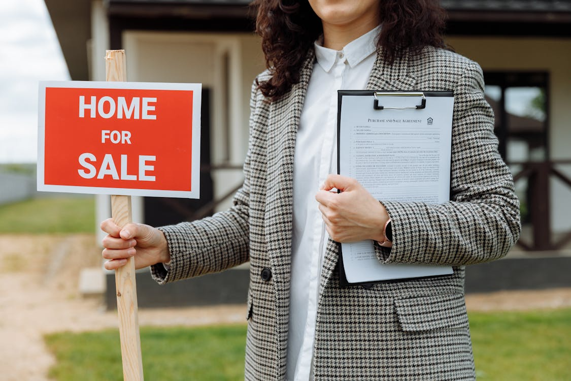 Real estate agent holding a home for sale listing, highlighting the cost of selling a home.