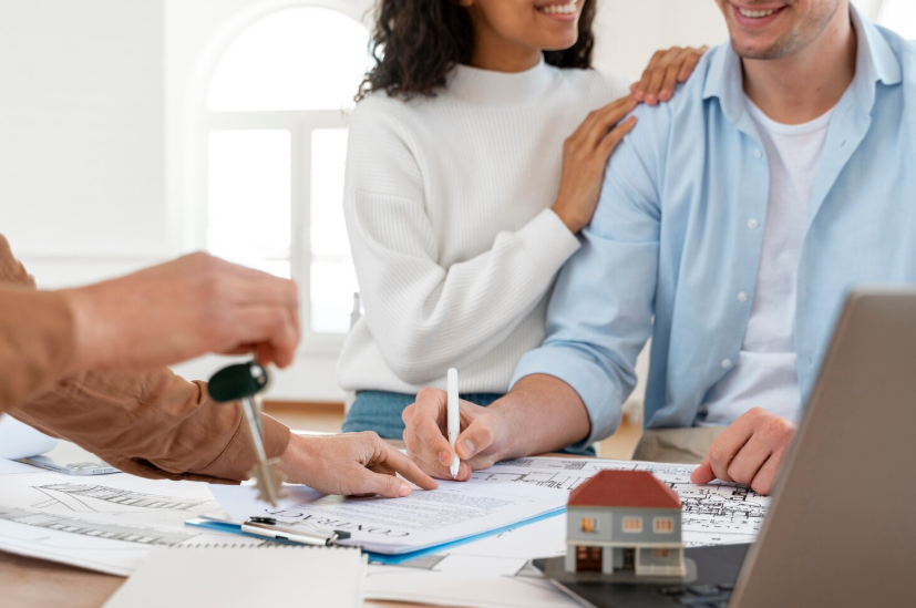 Couple signing home-related documents with a house model, symbolizing property value decisions.